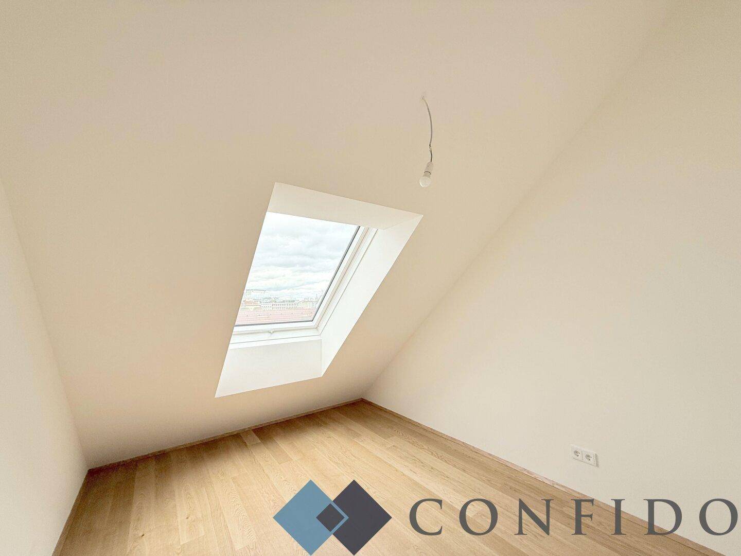 Helles Zimmer im Dachgeschoss mit Holzboden und einem großen Dachfenster.