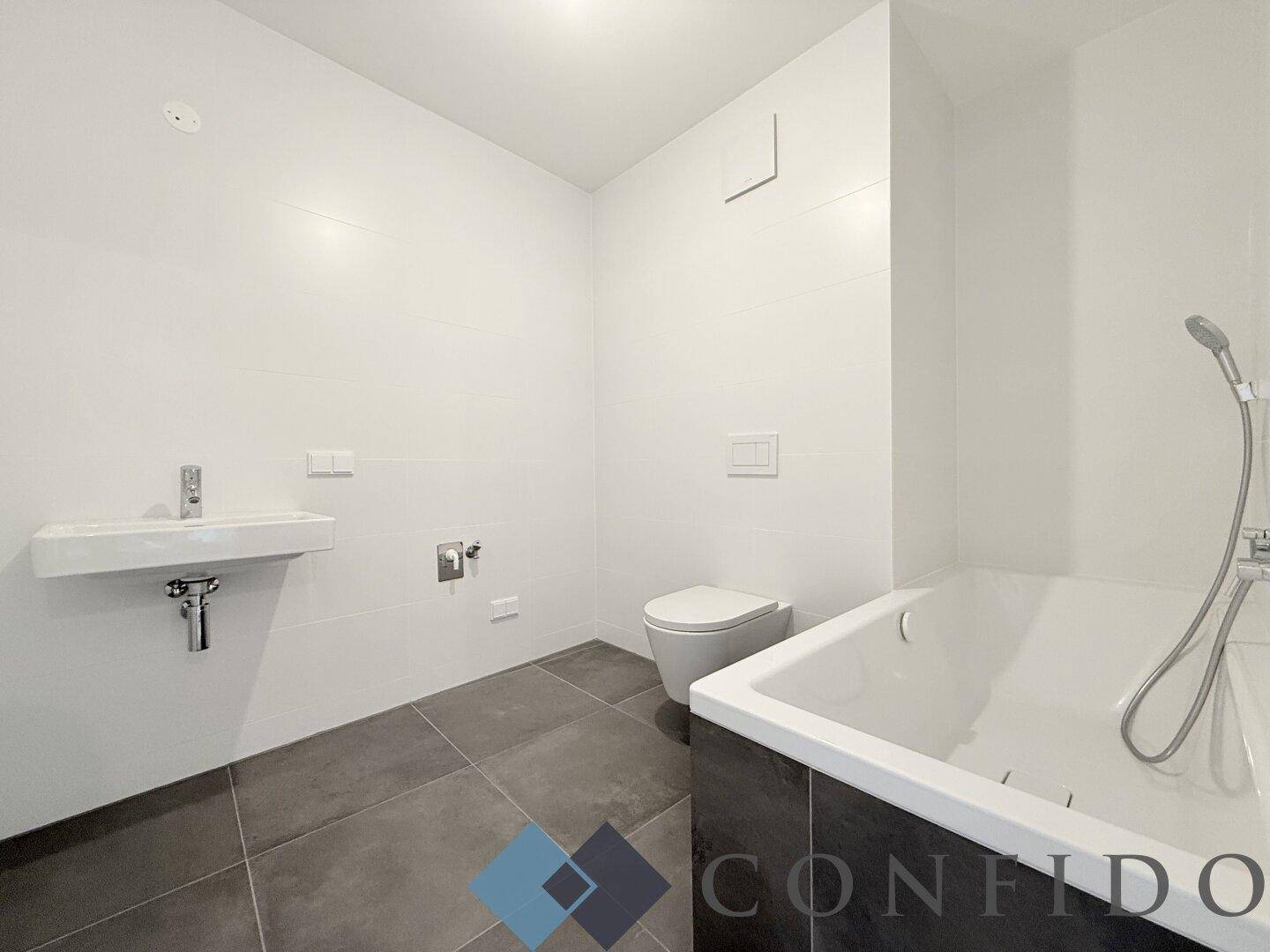 Modernes Badezimmer mit Badewanne, wandhängendem WC und schwebendem Waschbecken in Weiß und Grau.