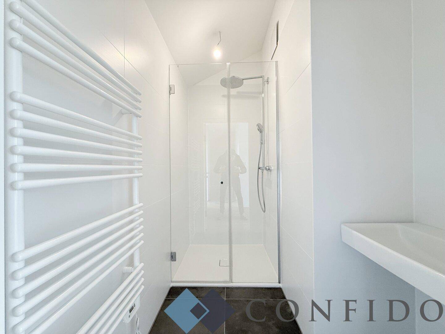 Modernes Badezimmer mit ebenerdiger Dusche und beheiztem Handtuchhalter in minimalistischem Design.