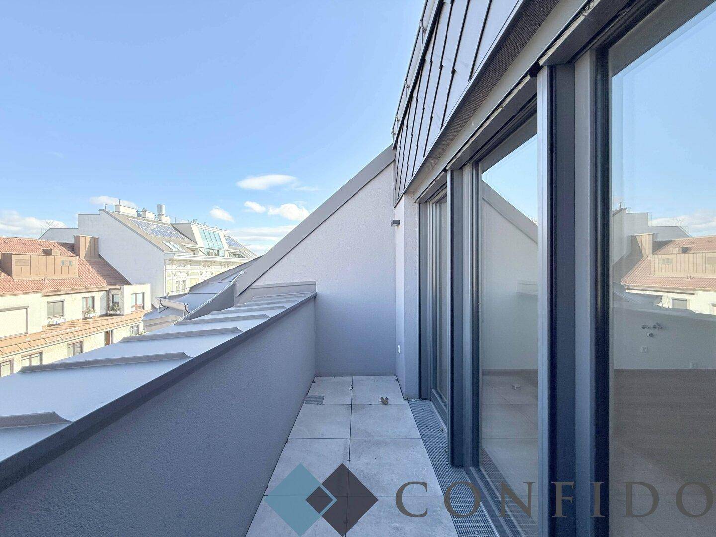 Schmaler Balkon mit Fliesenboden und Blick auf die umliegenden Dächer, ideal für frische Luft.