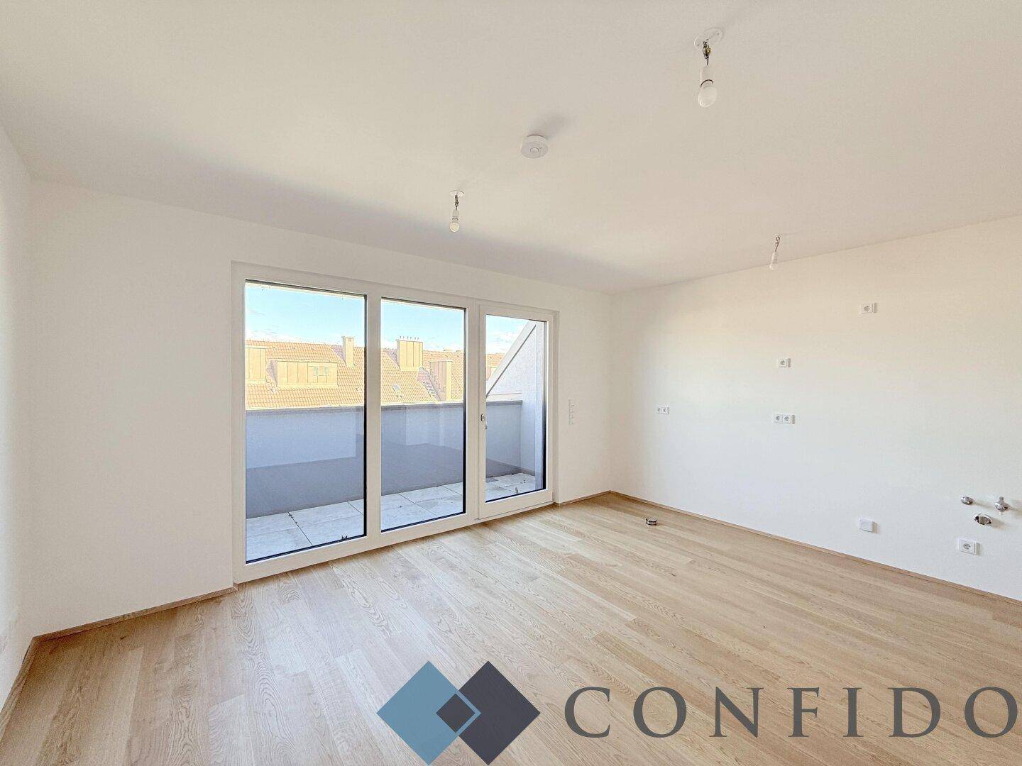 Helles, leeres Zimmer mit Holzboden und Zugang zu einer Terrasse, ideal als Wohnbereich.