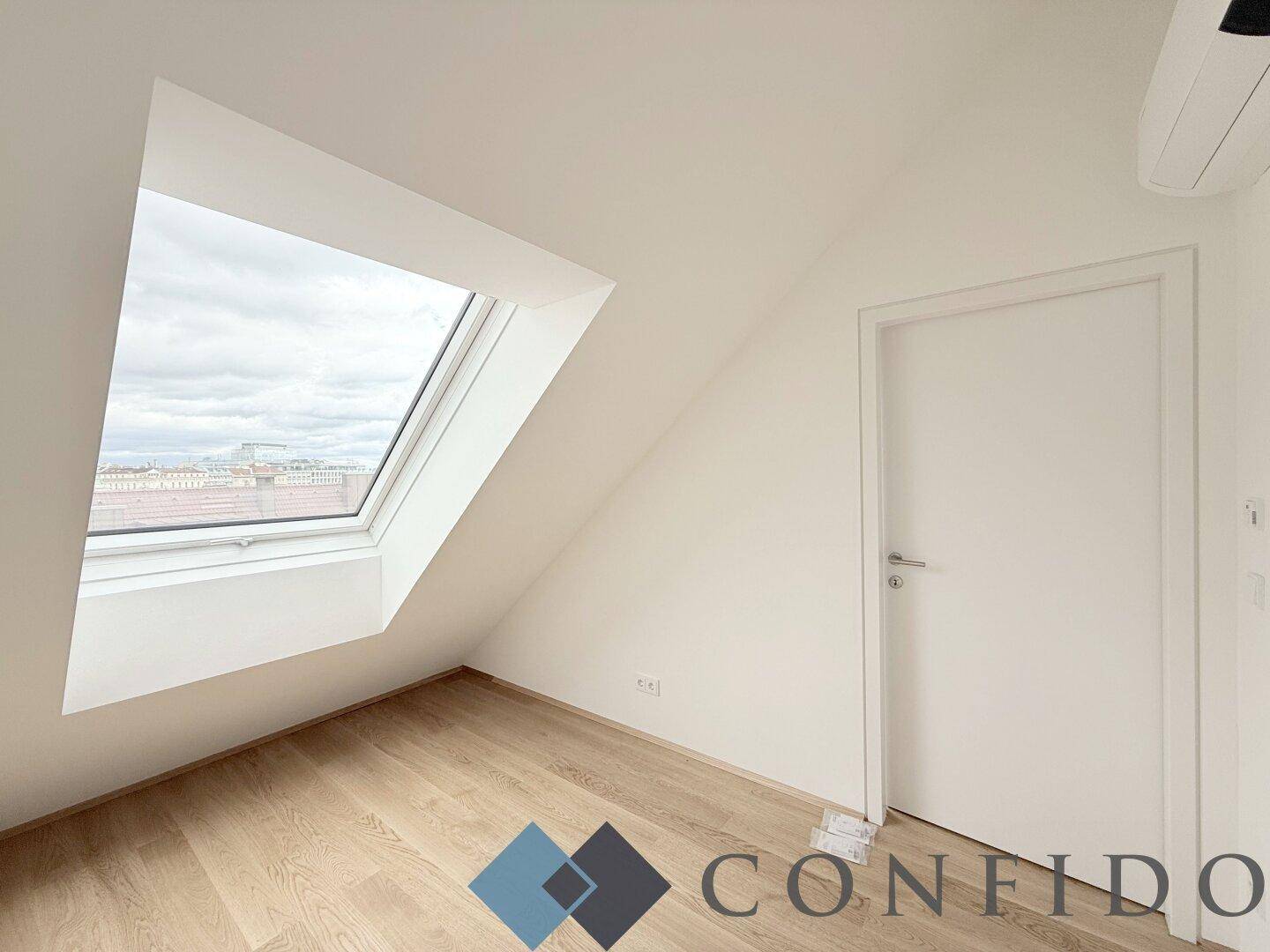 Helles Dachgeschosszimmer mit schräger Decke, Dachfenster und Holzboden, ideal als Schlafzimmer.