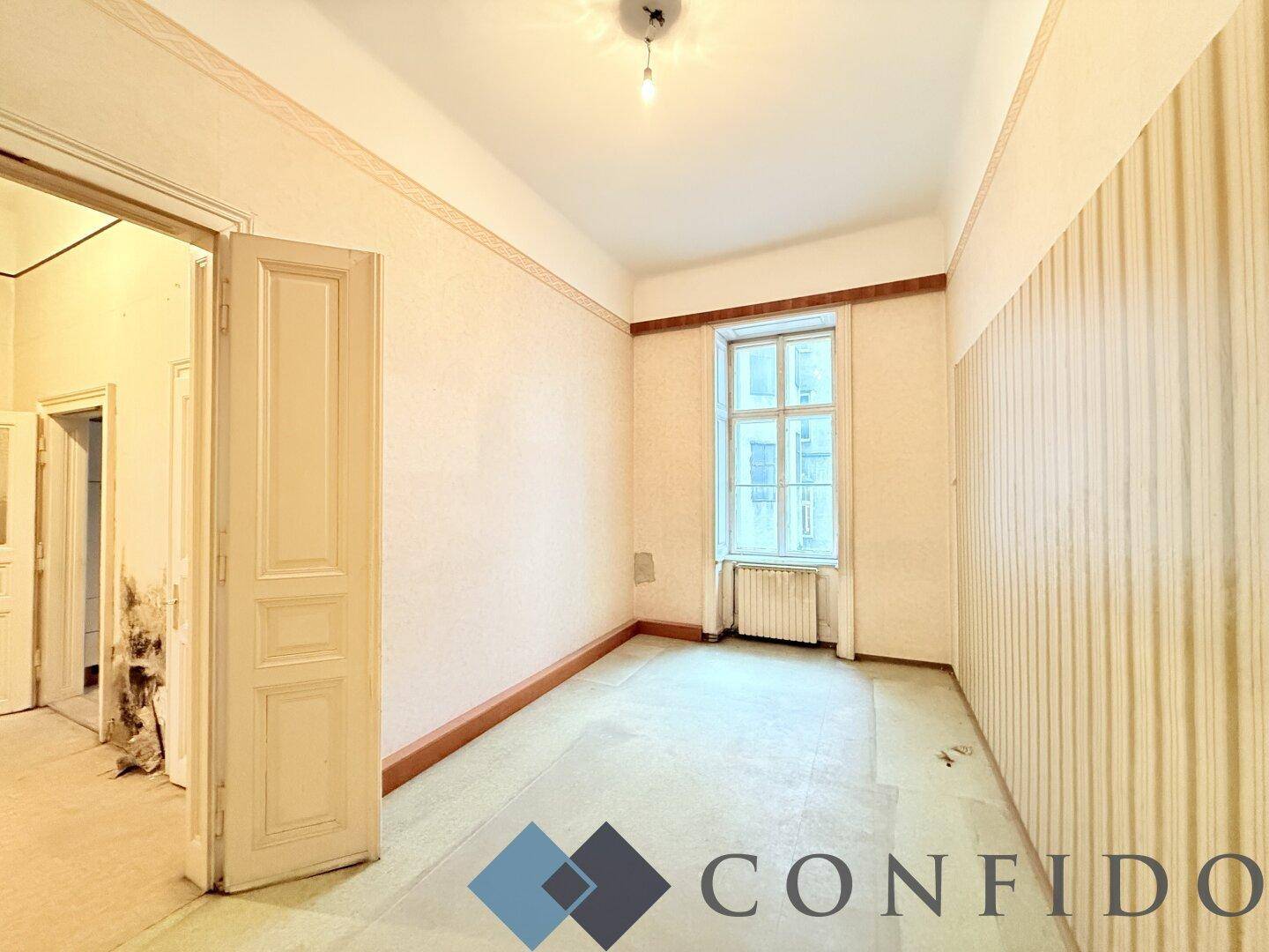 Unmöbliertes Zimmer mit Fenster und Tapeten, das Potenzial für eine individuelle Gestaltung bietet.