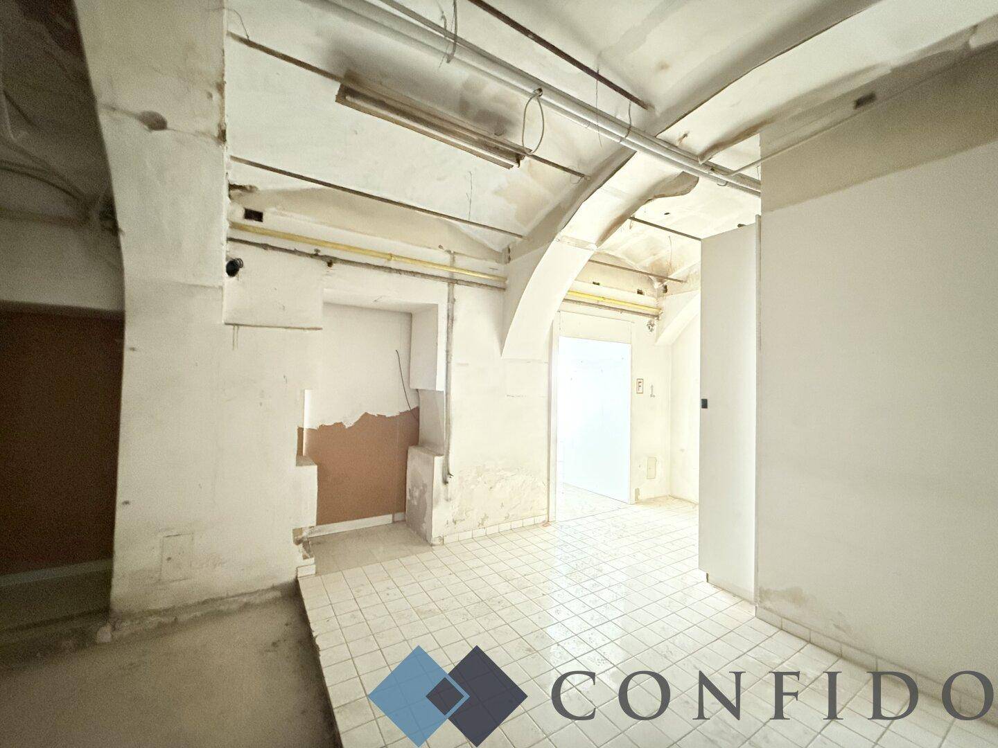 Hinterraum mit gewölbter Decke, Fliesenboden und sichtbaren Gebrauchsspuren, der eine Renovierung benötigt.