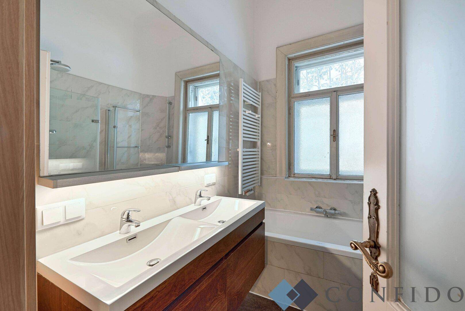 Modernes Badezimmer mit Doppelwaschbecken, Badewanne und Marmorfliesen.