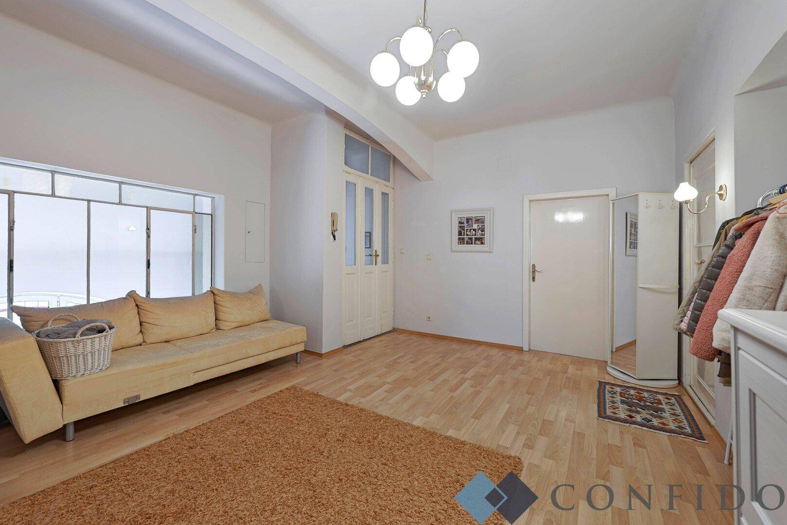 Heller Flurbereich mit Laminatboden, Sofa und Garderobe.