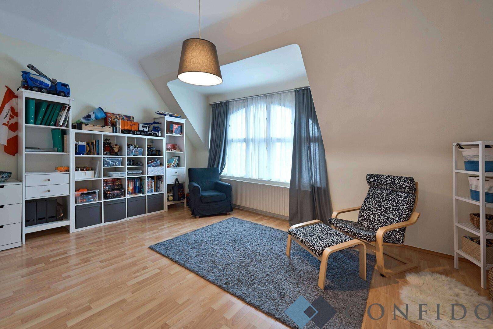 Kinderzimmer mit Laminatboden, Dachschräge und großem Fenster.