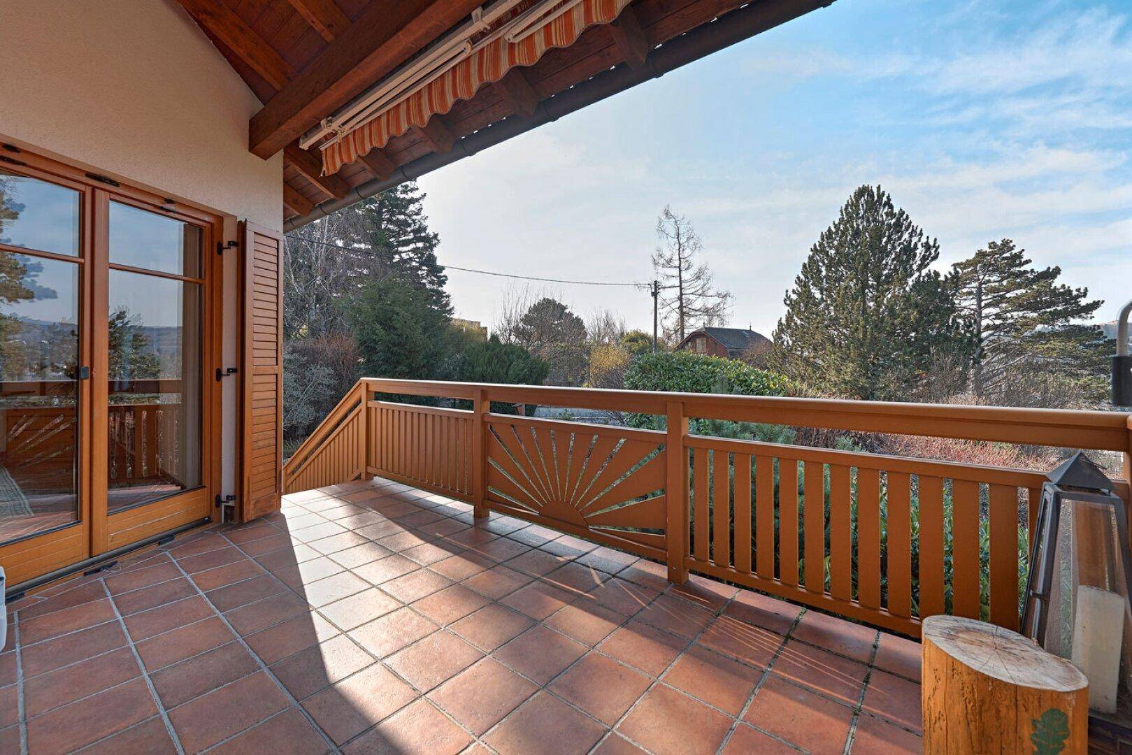 Geräumiger, überdachter Balkon mit Terrakottafliesen und Zugang vom Innenbereich des Hauses.