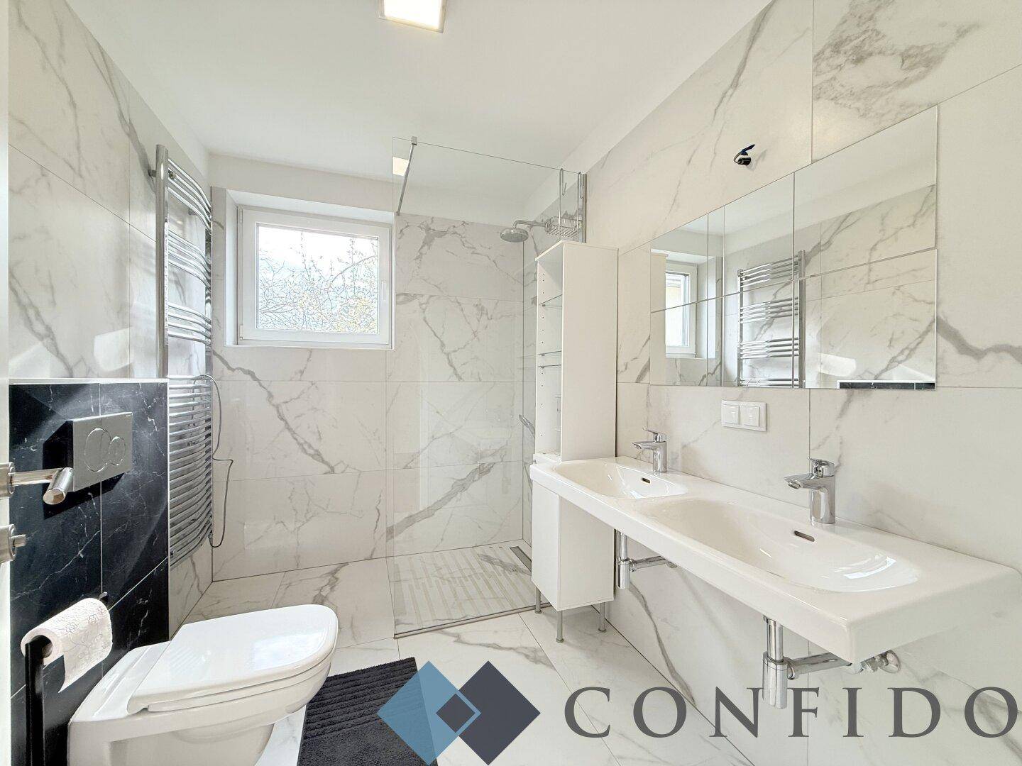 Großes modernes Badezimmer mit Doppelwaschbecken, begehbarer Dusche und beheiztem Handtuchhalter.