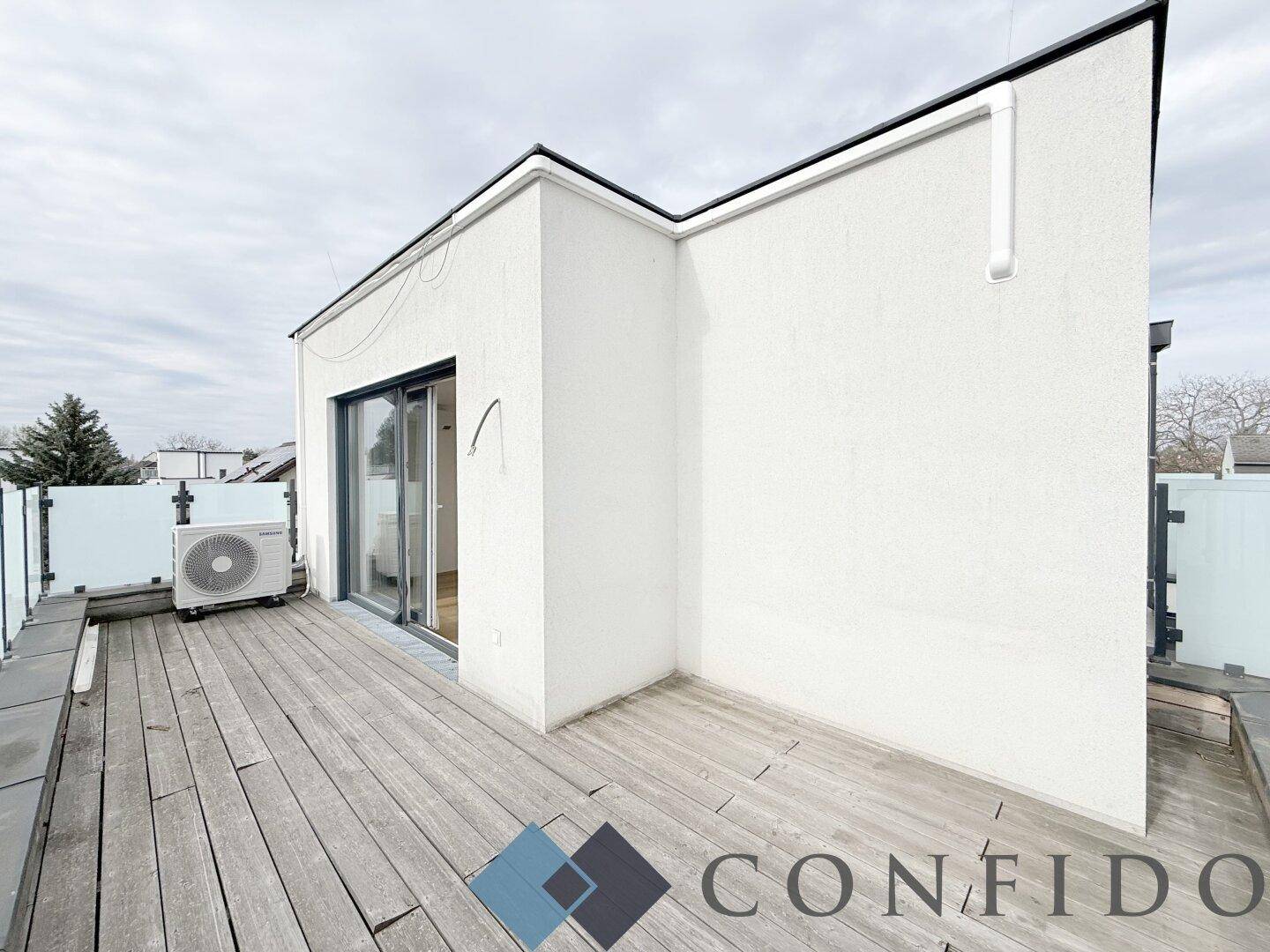 Weitläufige Holzterrasse mit moderner Fassade und Außeneinheit der Klimaanlage.