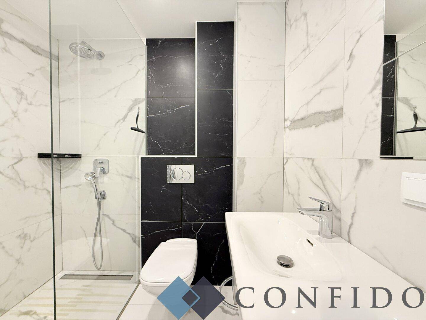 Modernes Badezimmer mit eleganten schwarz-weißen Marmorfliesen, Dusche und WC.