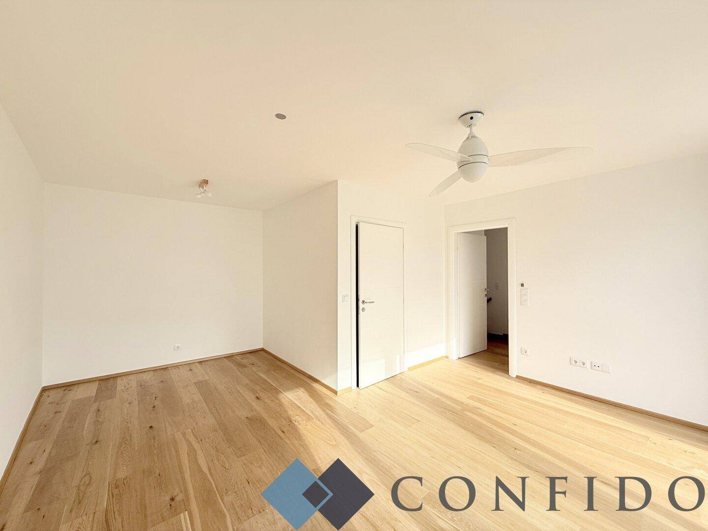 Geräumiges Zimmer mit hellem Holzboden und Deckenventilator, bereit zur individuellen Gestaltung.