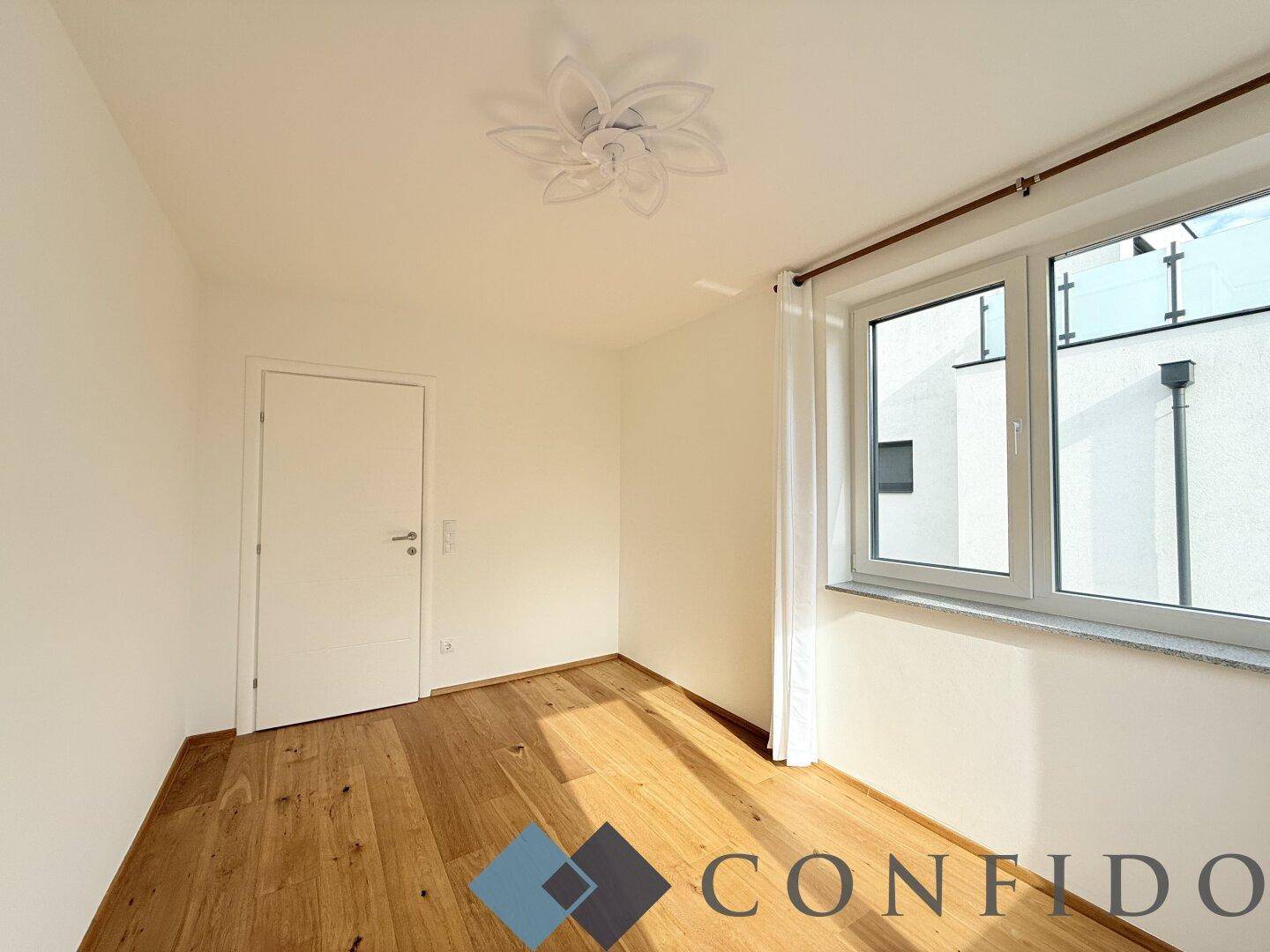 Ruhiges Schlafzimmer mit Holzboden und einem Fenster, das den Blick nach draußen freigibt.