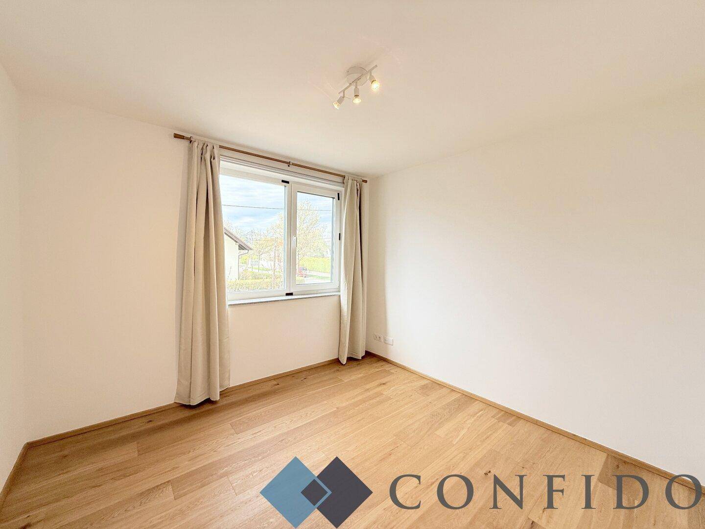 Helles und ruhiges Schlafzimmer mit Holzboden und Fenster, ideal als Kinder- oder Gästezimmer.