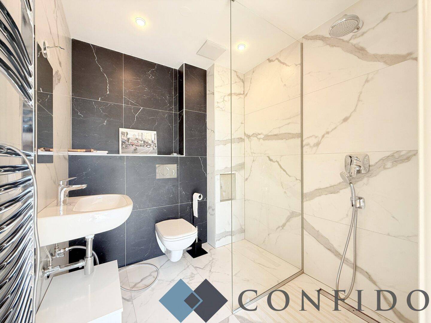 Modernes Badezimmer mit eleganten Marmorfliesen, begehbarer Dusche und wandhängendem WC.