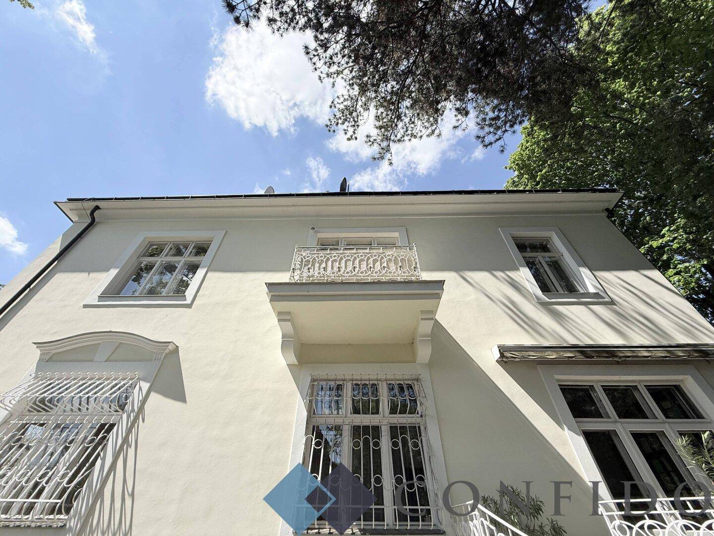 Detailansicht der Fassade mit elegantem Balkon und dekorativen Fenstergittern unter blauem Himmel.