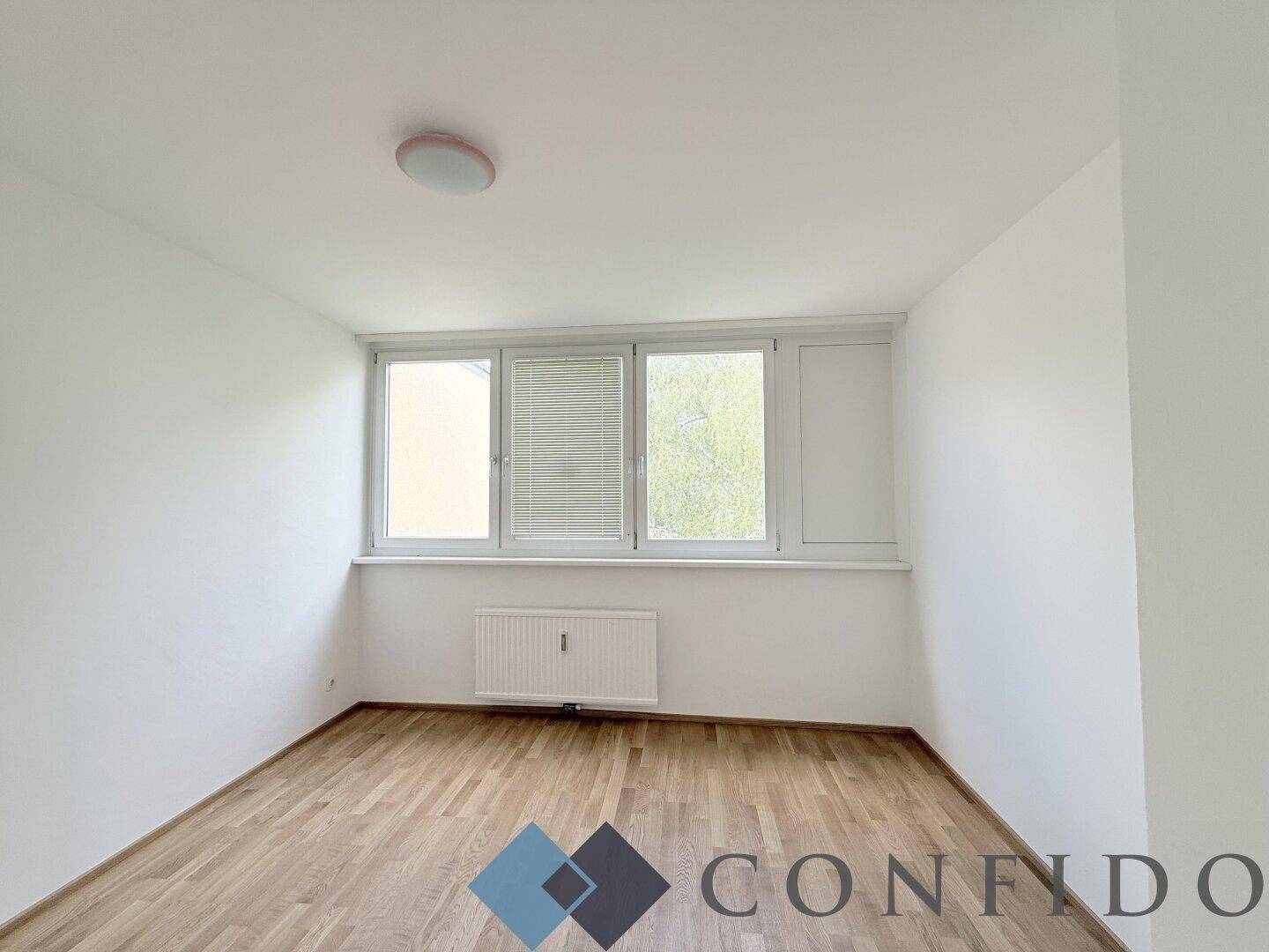 Helles Schlafzimmer mit Parkettboden und Fenster, bereit zur Einrichtung.