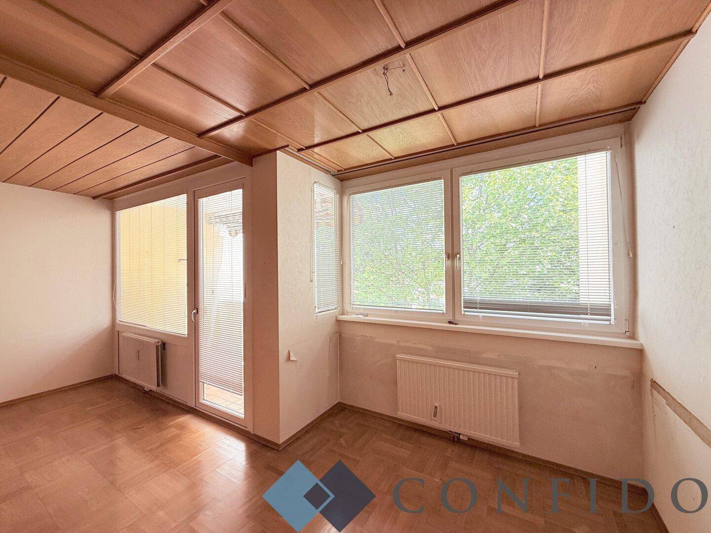 Wohnzimmer mit Holzdecke, Parkettboden und großen Fenstern für viel Tageslicht.