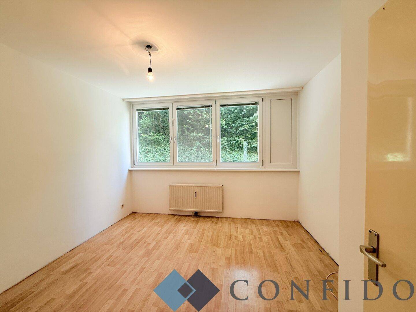 Ruhiges Schlafzimmer mit Parkettboden und Fensterblick ins Grüne, ideal für Erholung.