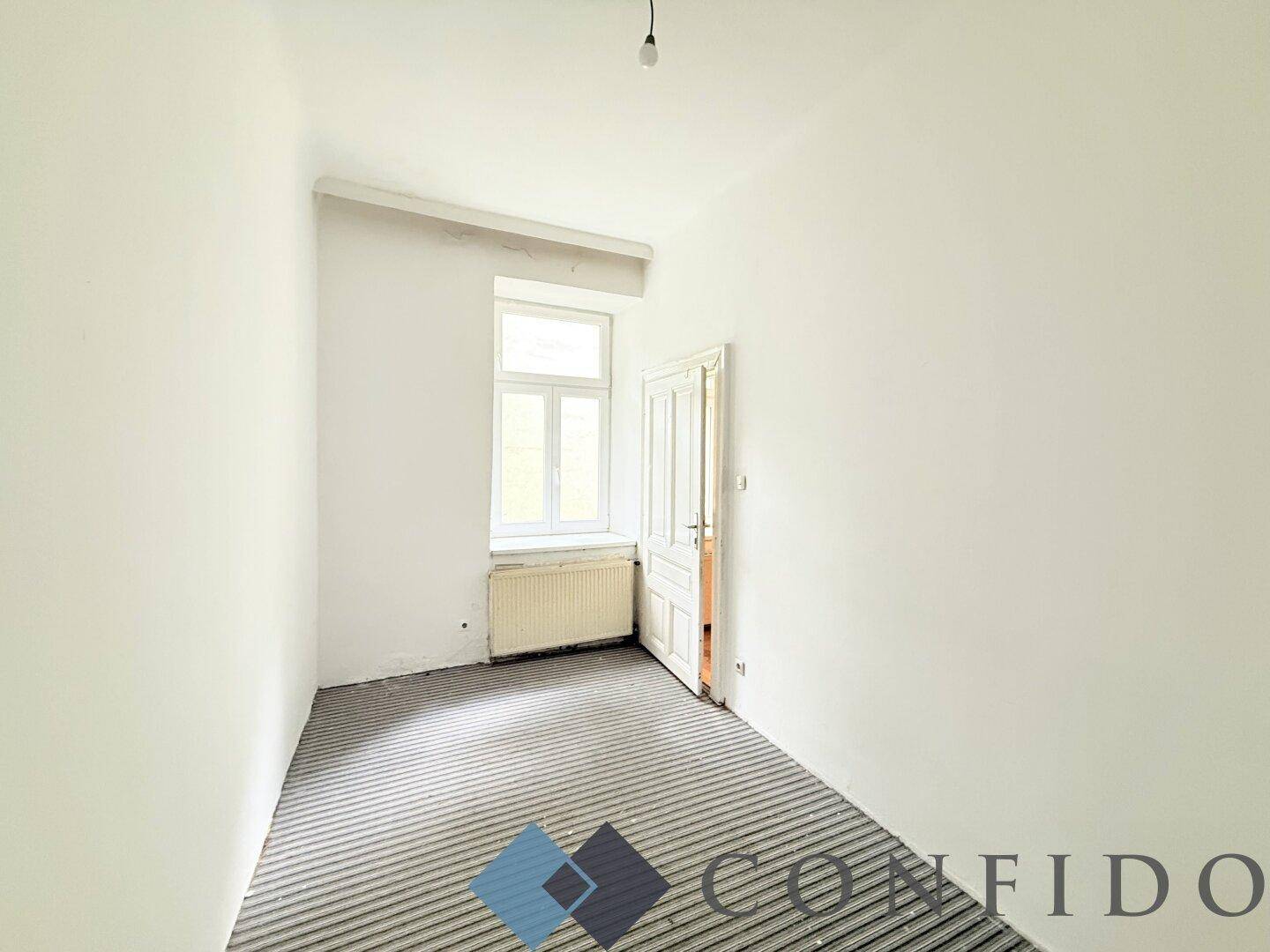 Leeres Zimmer mit einem Fenster und vorbereitetem Boden für die Installation neuer Beläge.