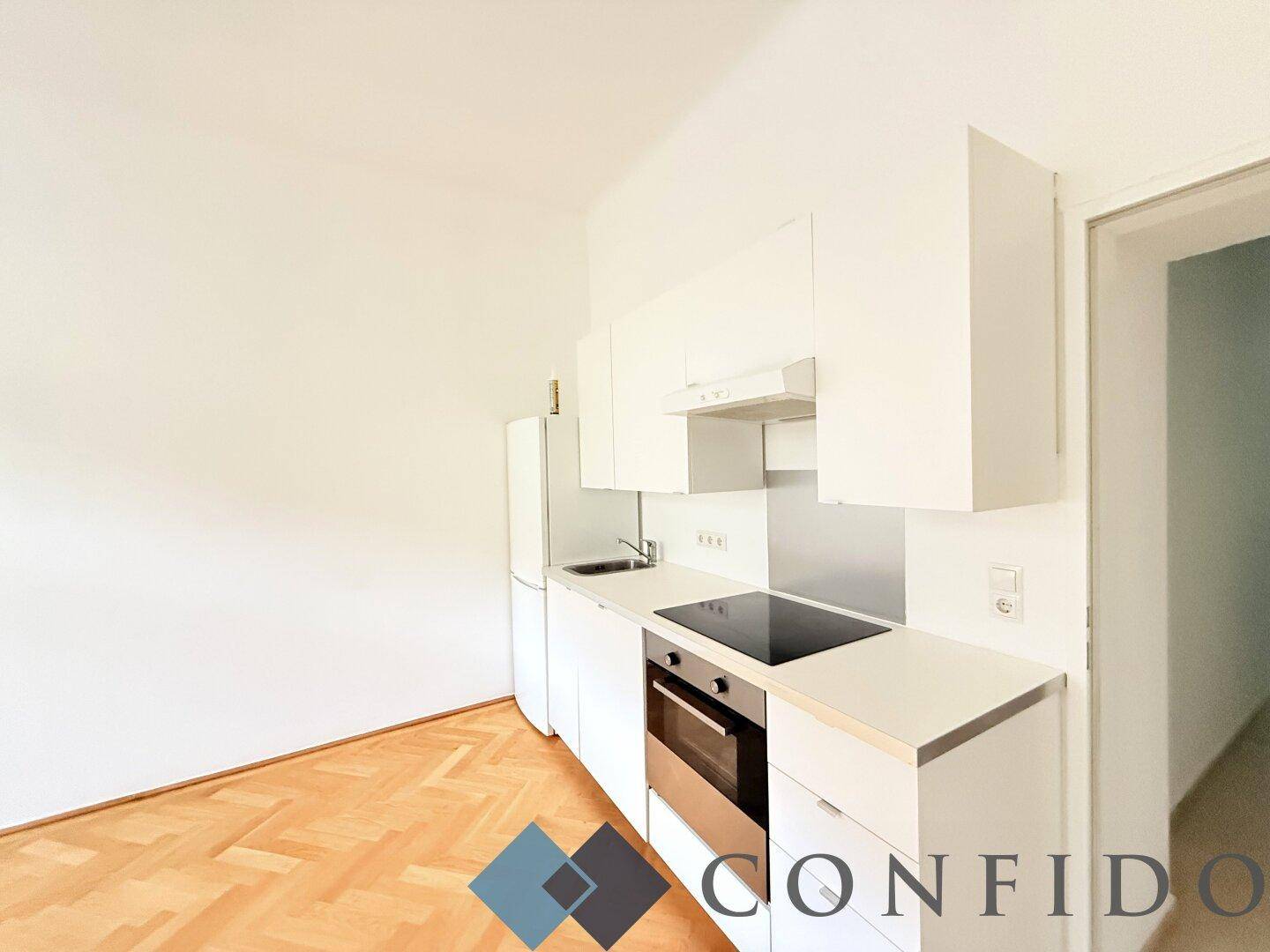 Moderne Küchenzeile mit weißen Schränken, Induktionskochfeld und integriertem Backofen.