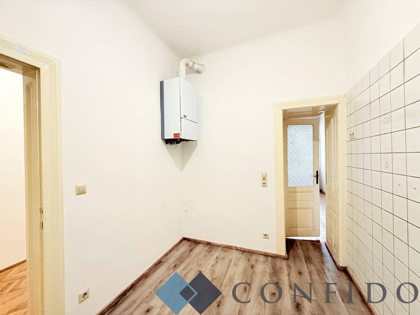 Küchenbereich mit Gastherme an der Wand und gefliesten Abschnitten, ideal für eine Neugestaltung.