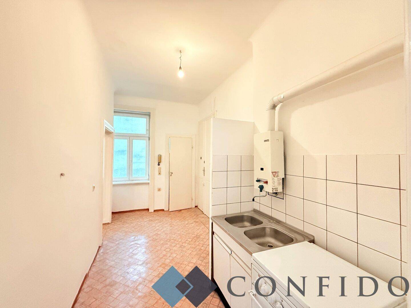 Funktionale Küche mit Doppelspülbecken, Waschmaschine und Gastherme, bereit zur Modernisierung.