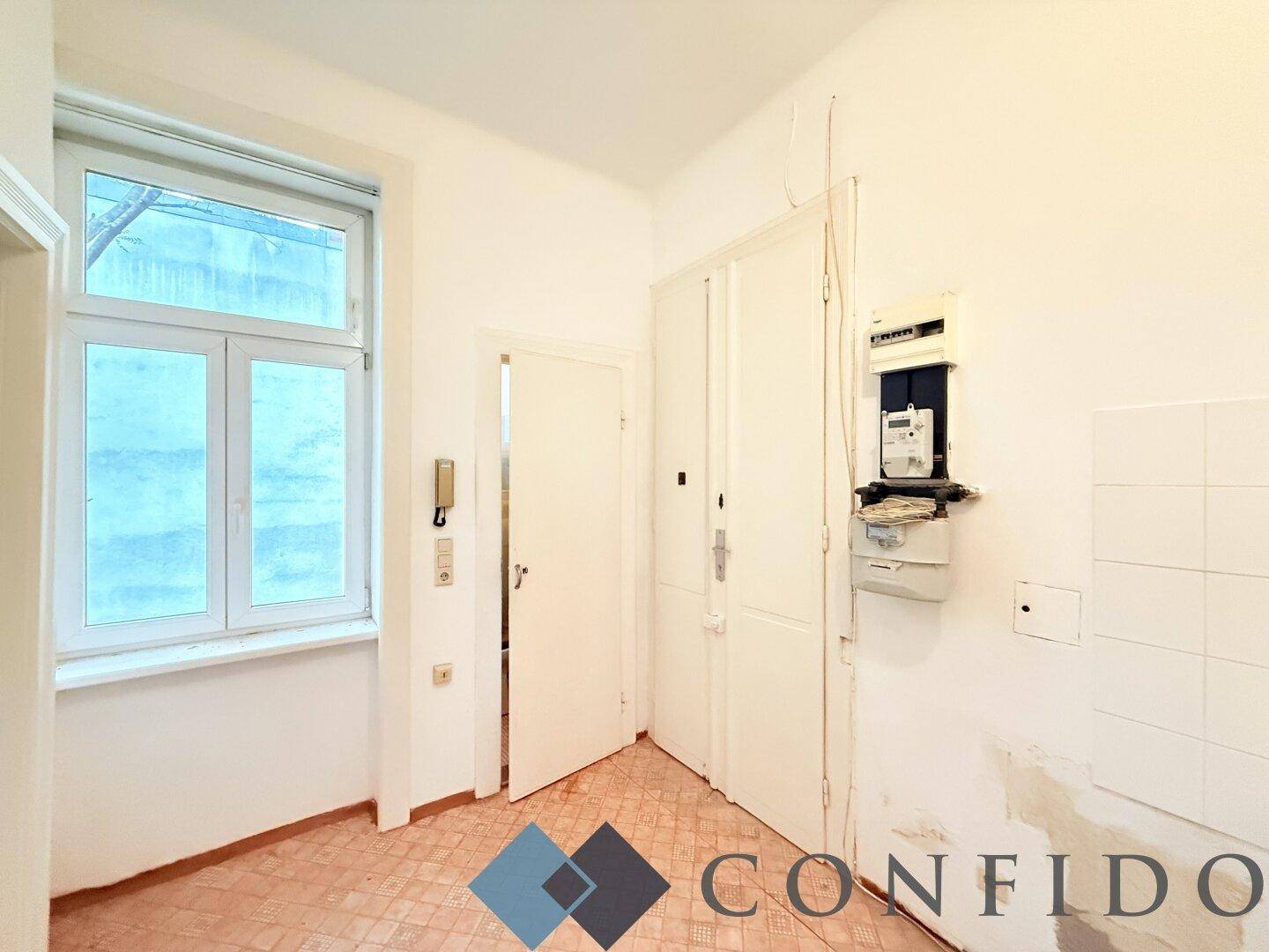 Helle Küchennische mit Fenster und Zugang zu weiteren Räumen, ideal für eine neue Einbauküche.