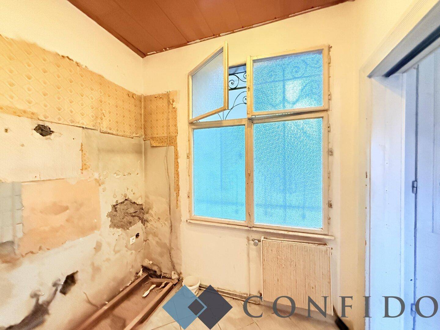 Küche in Renovierung mit freigelegten Wänden, Fenster und Holzdeckenverkleidung.