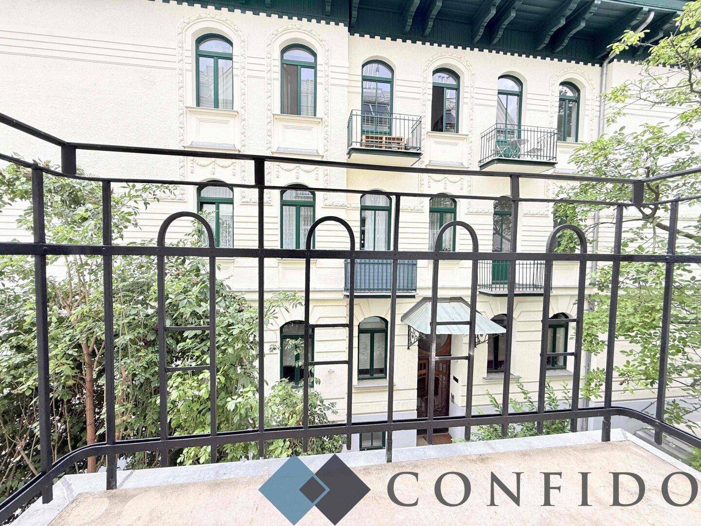 Blick vom Balkon auf die historische Fassade des Gebäudes mit grünen Fensterläden.