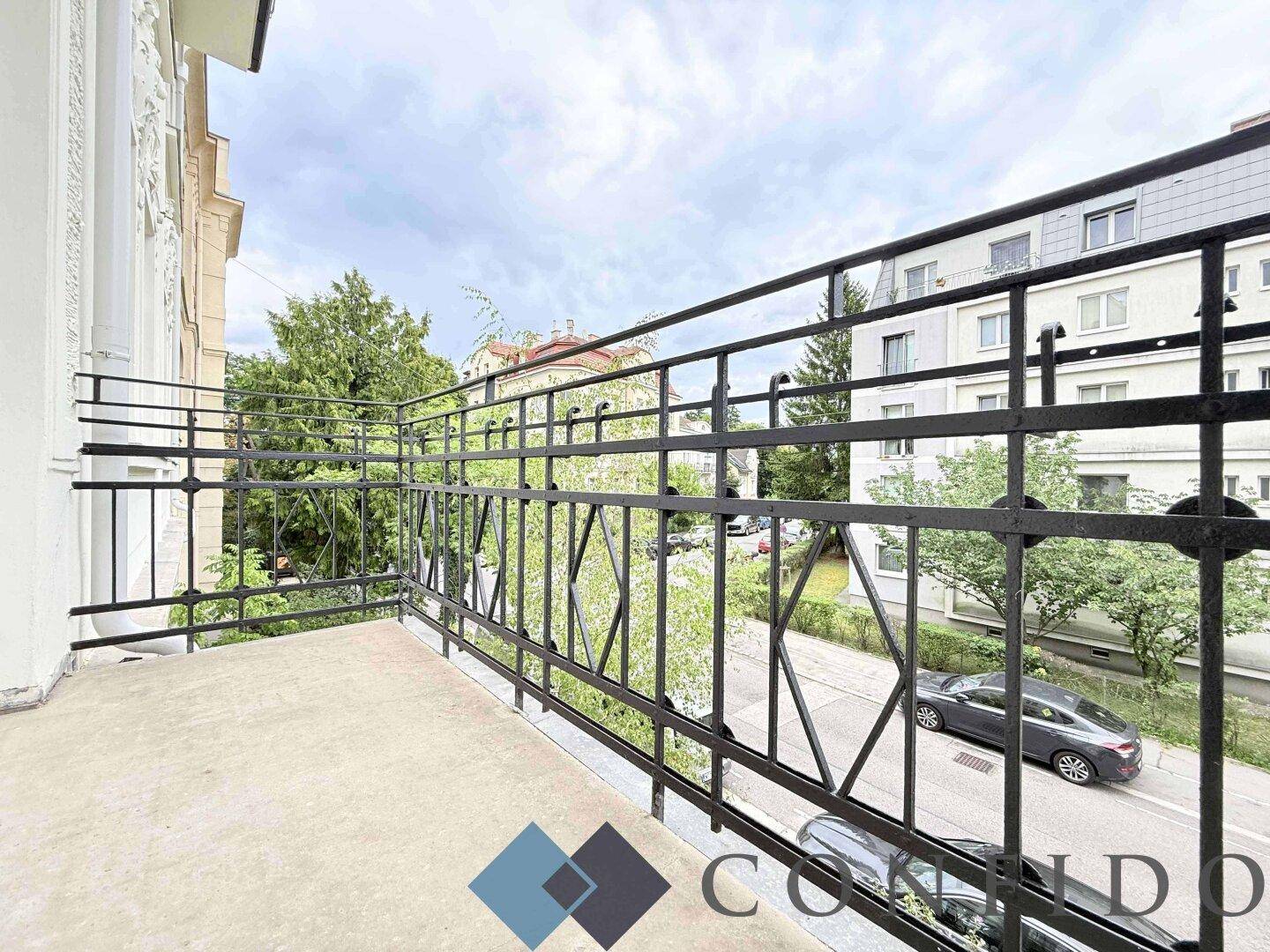 Balkon mit schmiedeeisernem Geländer und Blick auf die Straße und umliegende Gebäude.