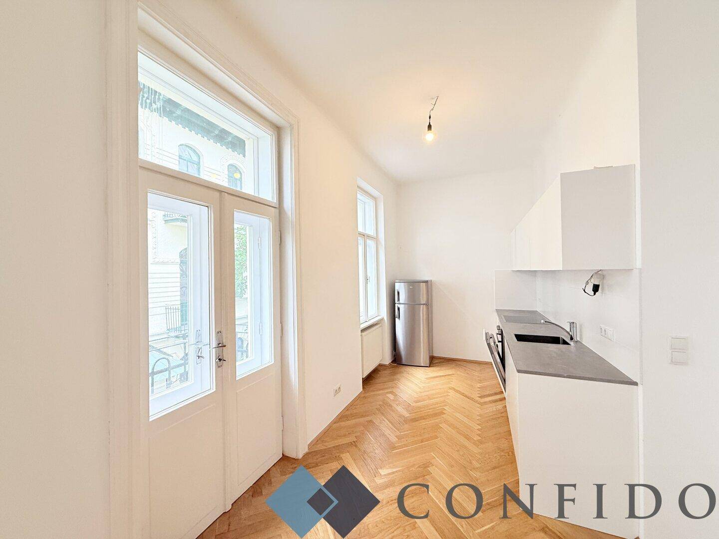 Moderne Küchenzeile mit weißen Schränken und Zugang zu einem französischen Balkon.