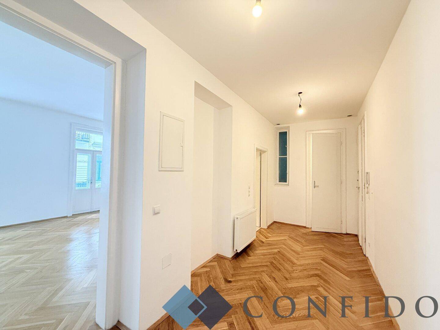 Langer Flur mit Fischgrätparkett und Zugang zu weiteren Räumen der Wohnung.