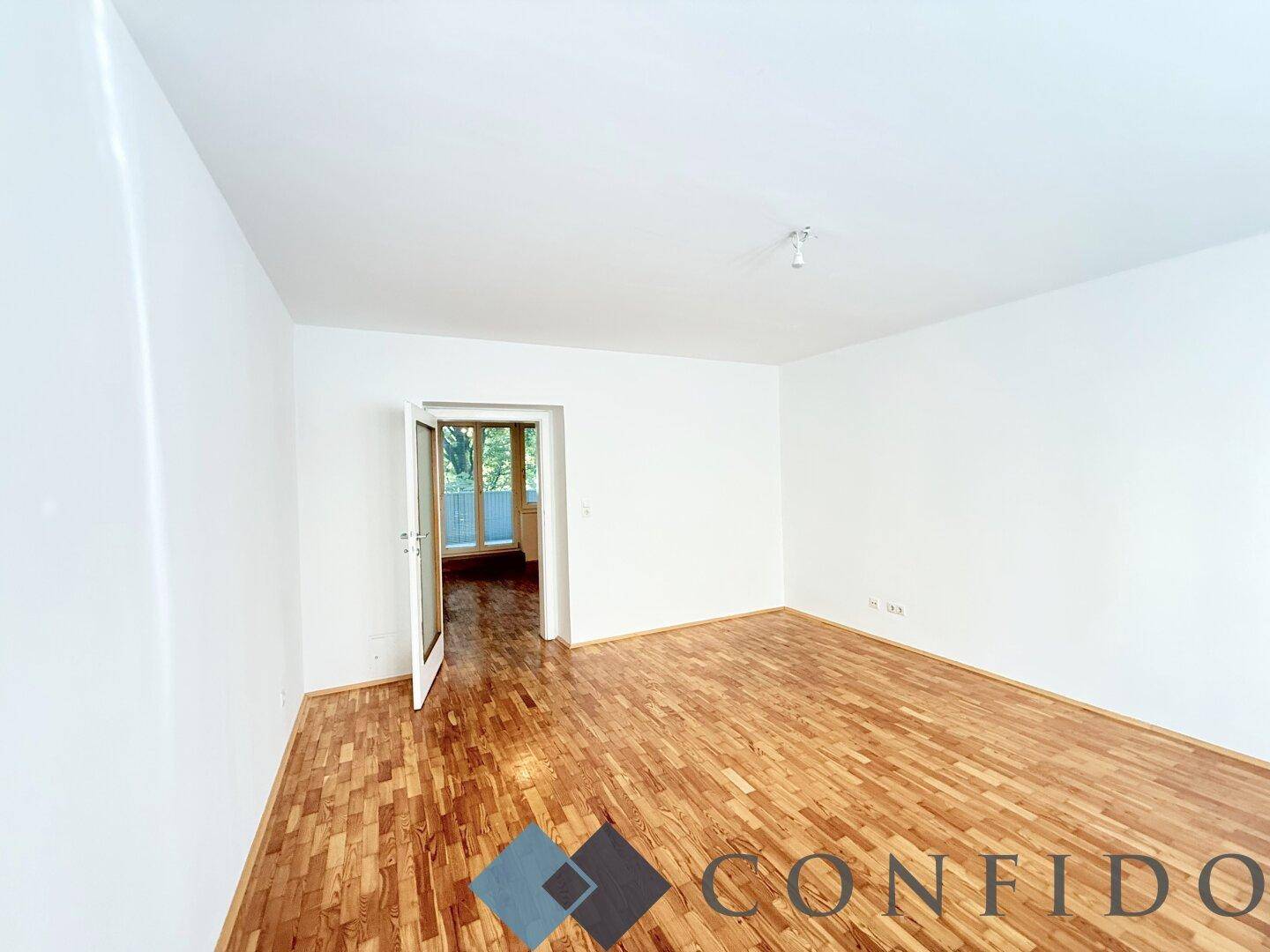 Helles Zimmer mit Parkettboden und direktem Zugang zum Balkon, ideal für ein offenes Wohnkonzept.