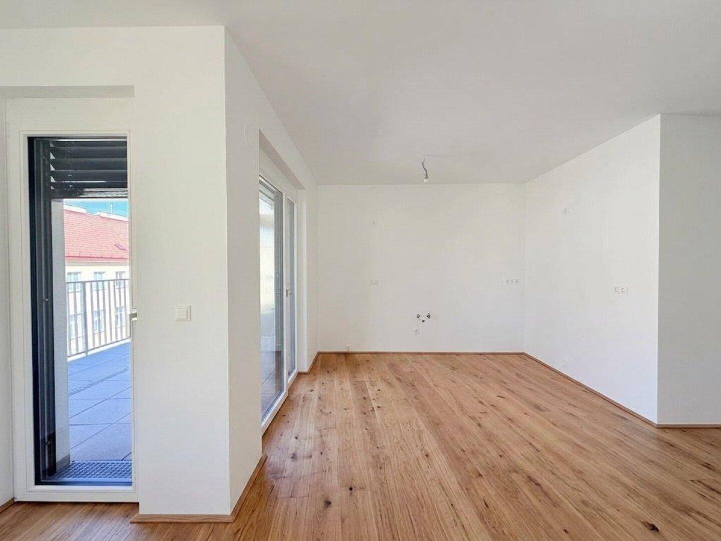 Heller Wohnbereich mit Holzboden und Zugang zu einem Außenbereich, ideal für offenes Wohnen.