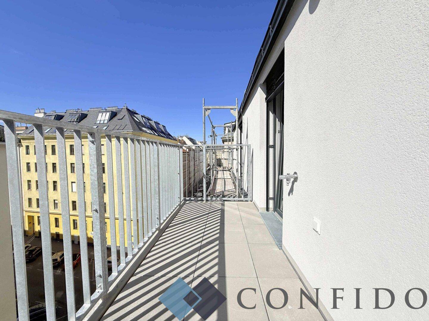 Langer, schmaler Balkon mit Fliesenboden und Blick auf die Stadt, ideal für frische Luft.