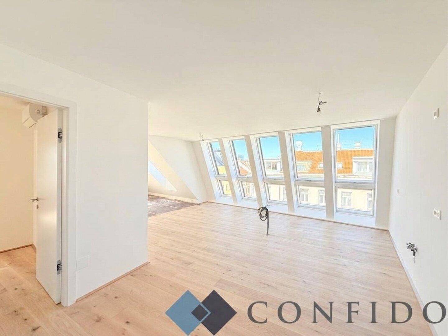 Großer, heller Raum im Dachgeschoss mit Holzboden und schrägen Fenstern für viel Licht.