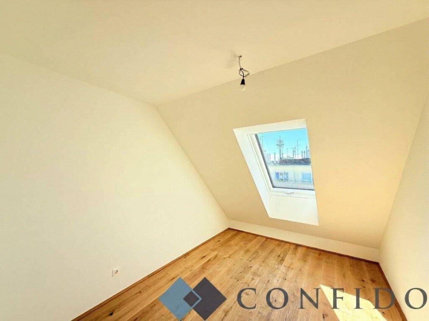 Gemütliches Dachzimmer mit Holzboden und einem einzelnen Dachfenster für natürliches Licht.