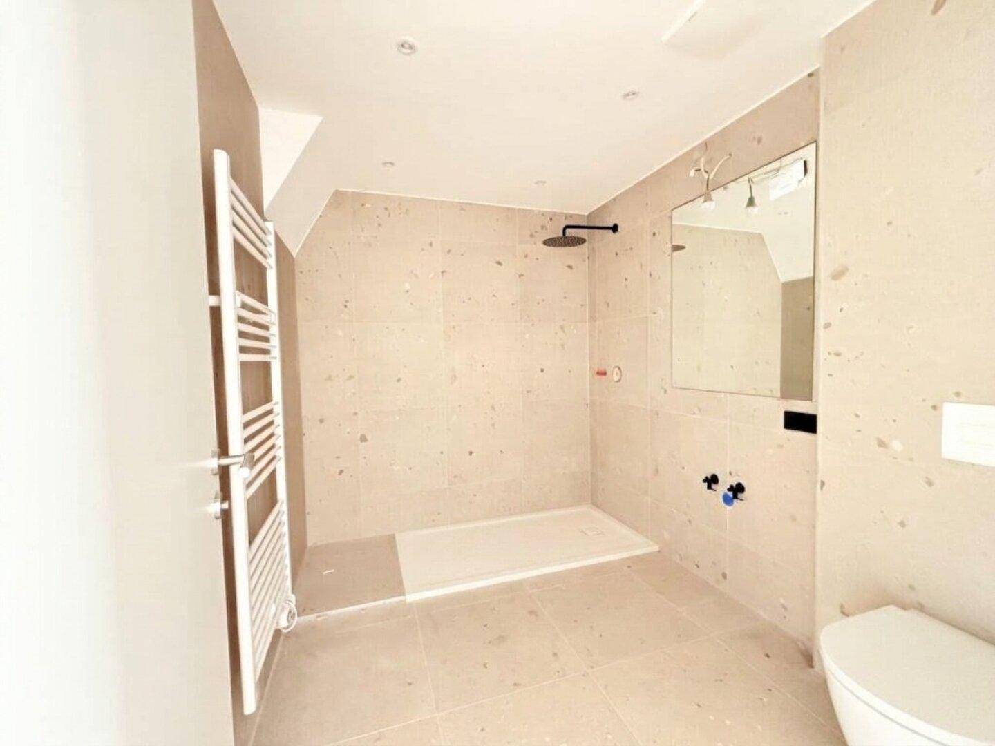 Modernes Badezimmer in Bau mit ebenerdiger Dusche, Wand-WC und beigefarbenen Fliesen.