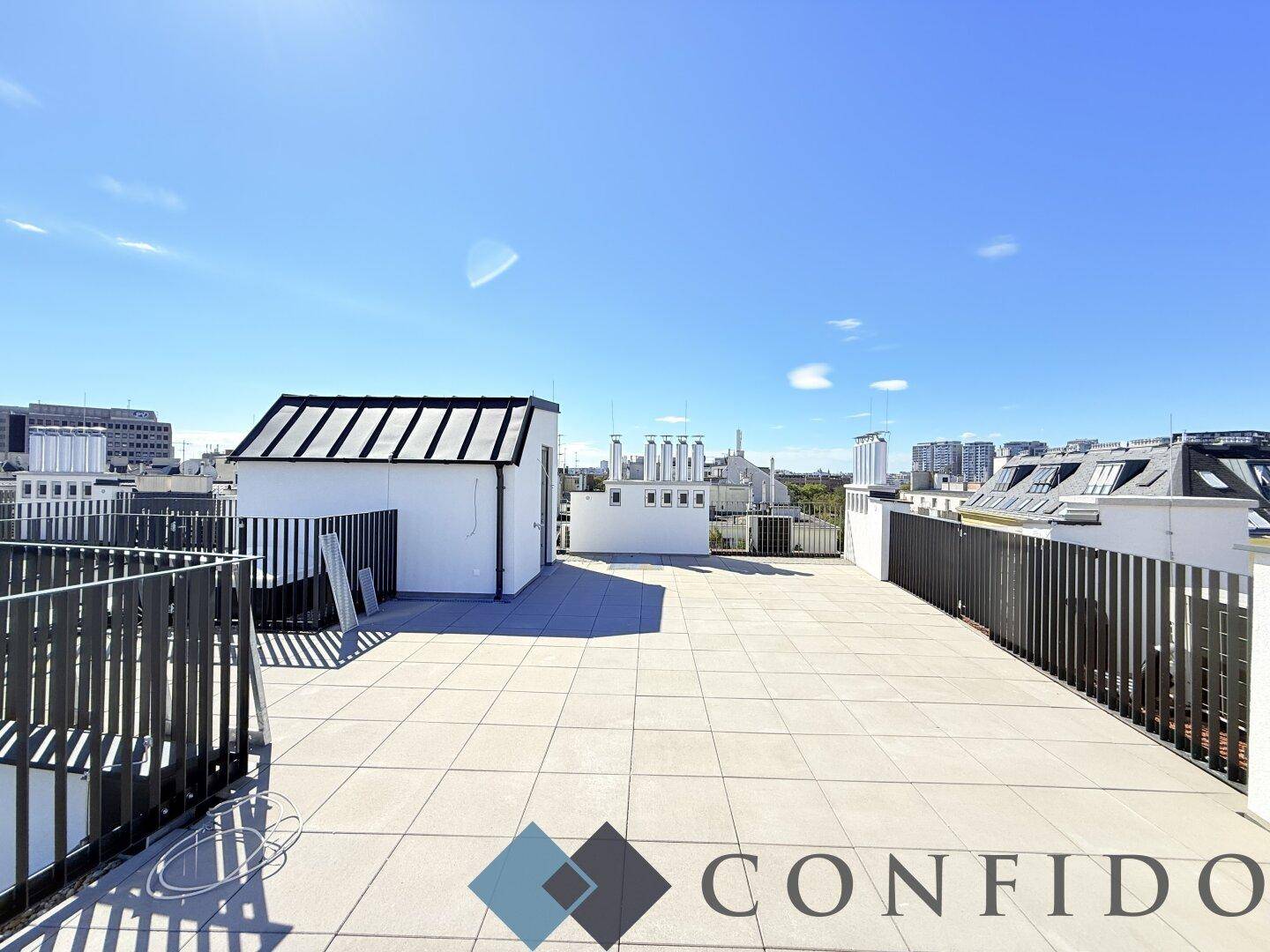 Weitläufige Dachterrasse mit einem kleinen Gebäude und Panoramablick über die Stadt.
