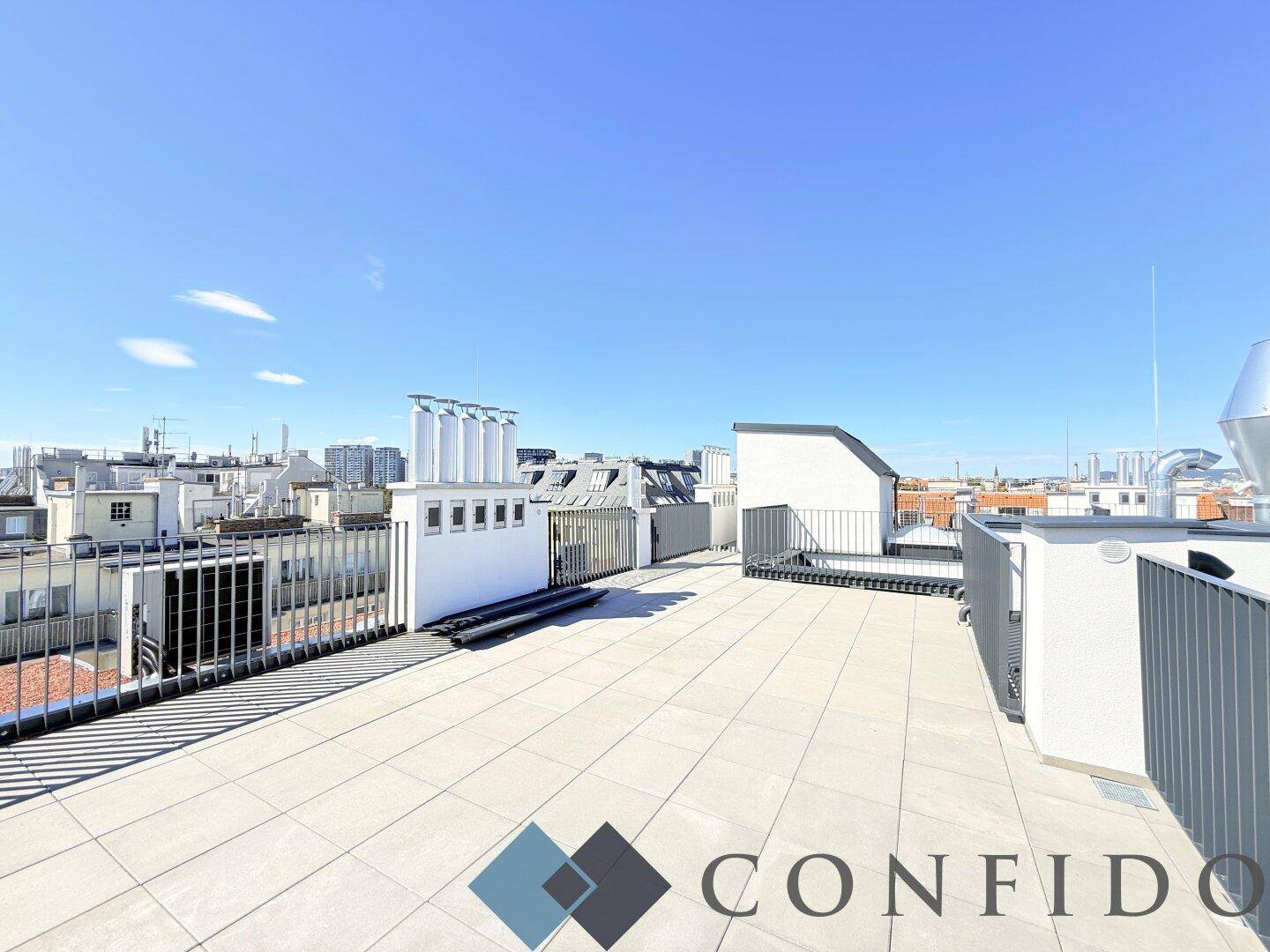 Weitläufige Dachterrasse mit Fliesenboden und Blick auf die umliegende Stadtlandschaft.