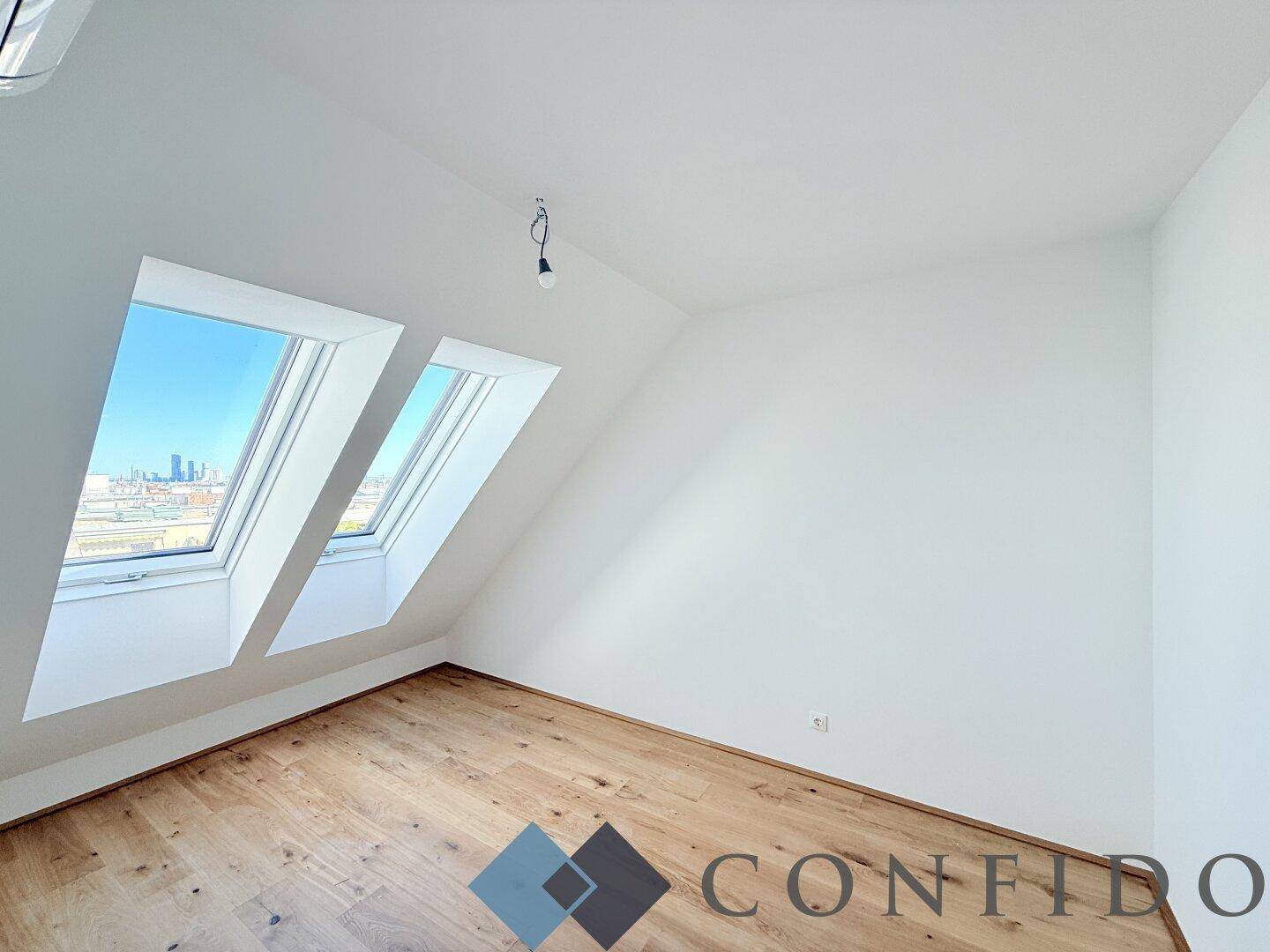 Helles Schlafzimmer mit Holzboden und Dachfenstern, die einen Blick auf die Stadt bieten.