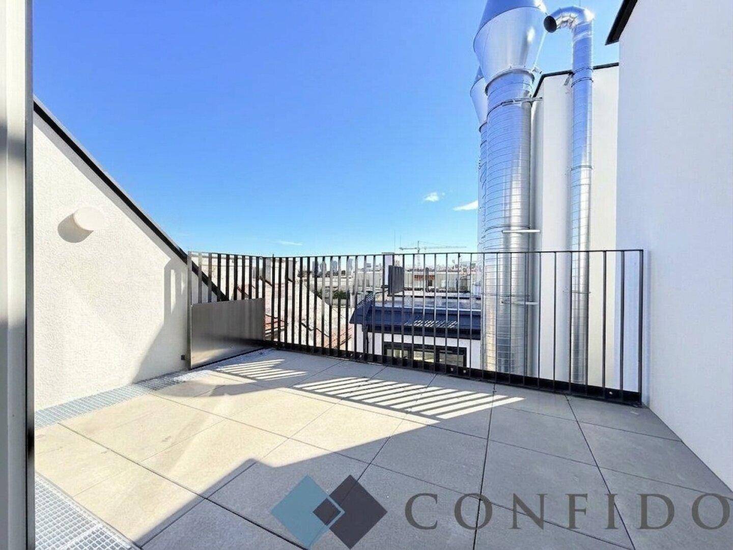 Moderne Dachterrasse mit Metallgeländer und Blick auf die Stadt.