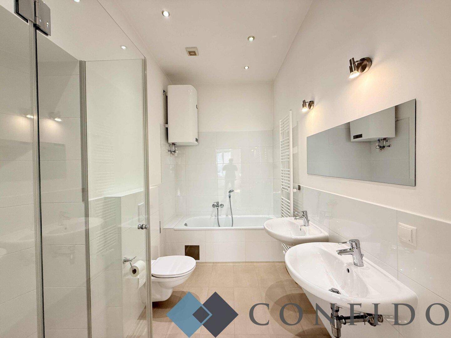 Modernes Badezimmer mit Badewanne, Dusche, Doppelwaschbecken und weiß gefliesten Wänden.