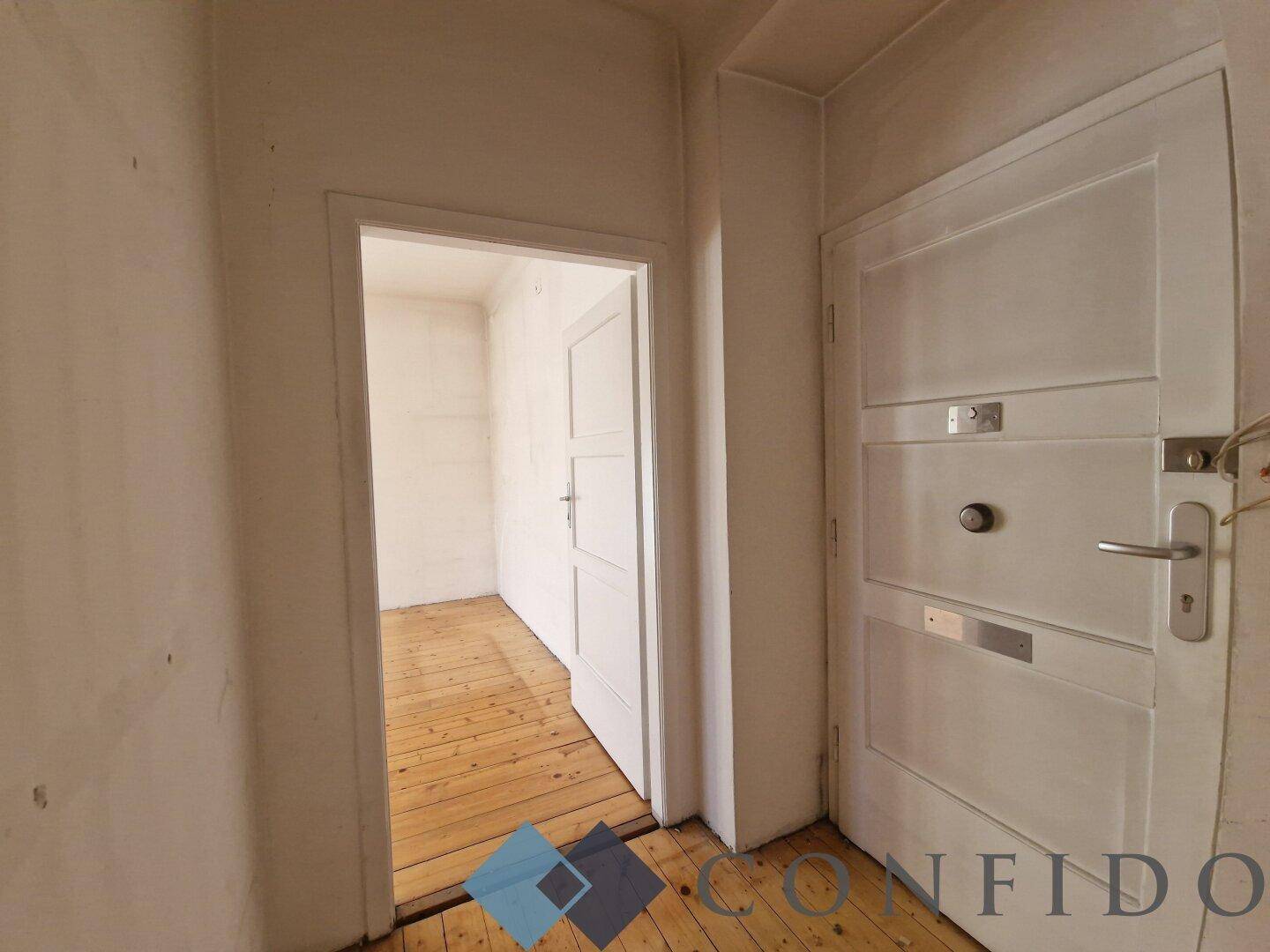 Eingangsbereich mit Holzdielenboden und Zugang zu den weiteren Räumen der Wohnung.