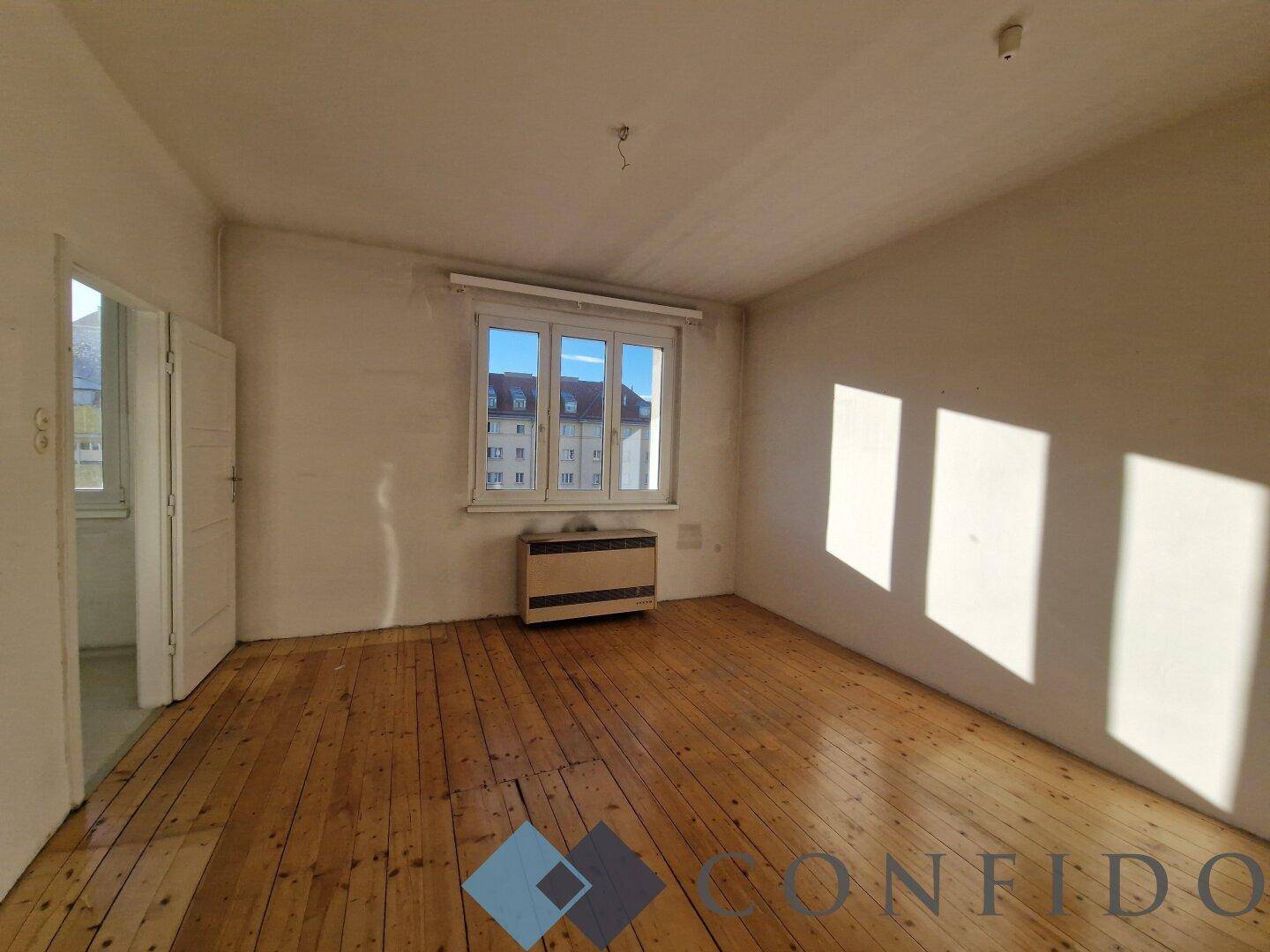 Sonniger Wohnraum mit Holzdielen und viel Tageslicht durch das Fenster.