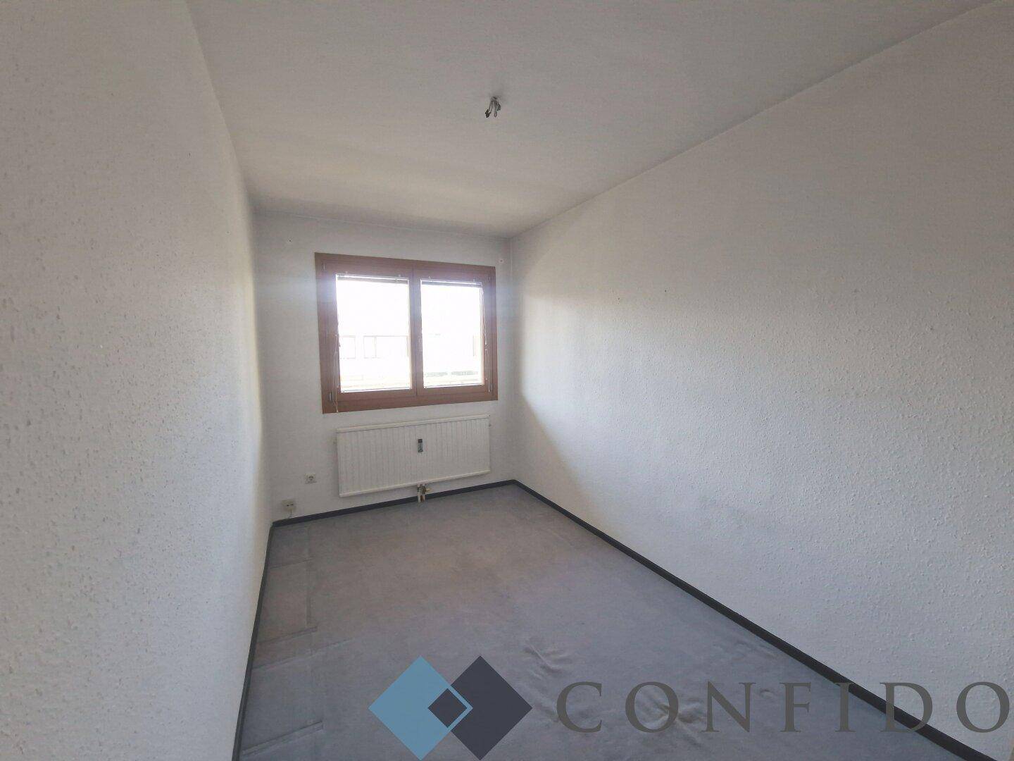 Kleines, helles Zimmer mit Fenster und Heizkörper, ideal als Büro oder Kinderzimmer.