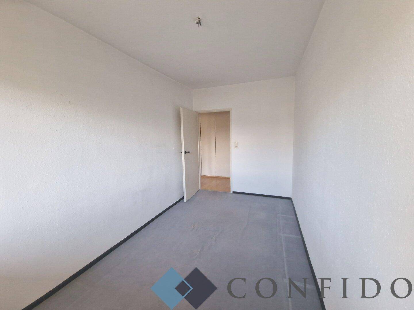 Leeres Zimmer mit weiß gestrichenen Wänden und Zugang zu einem weiteren Raum.