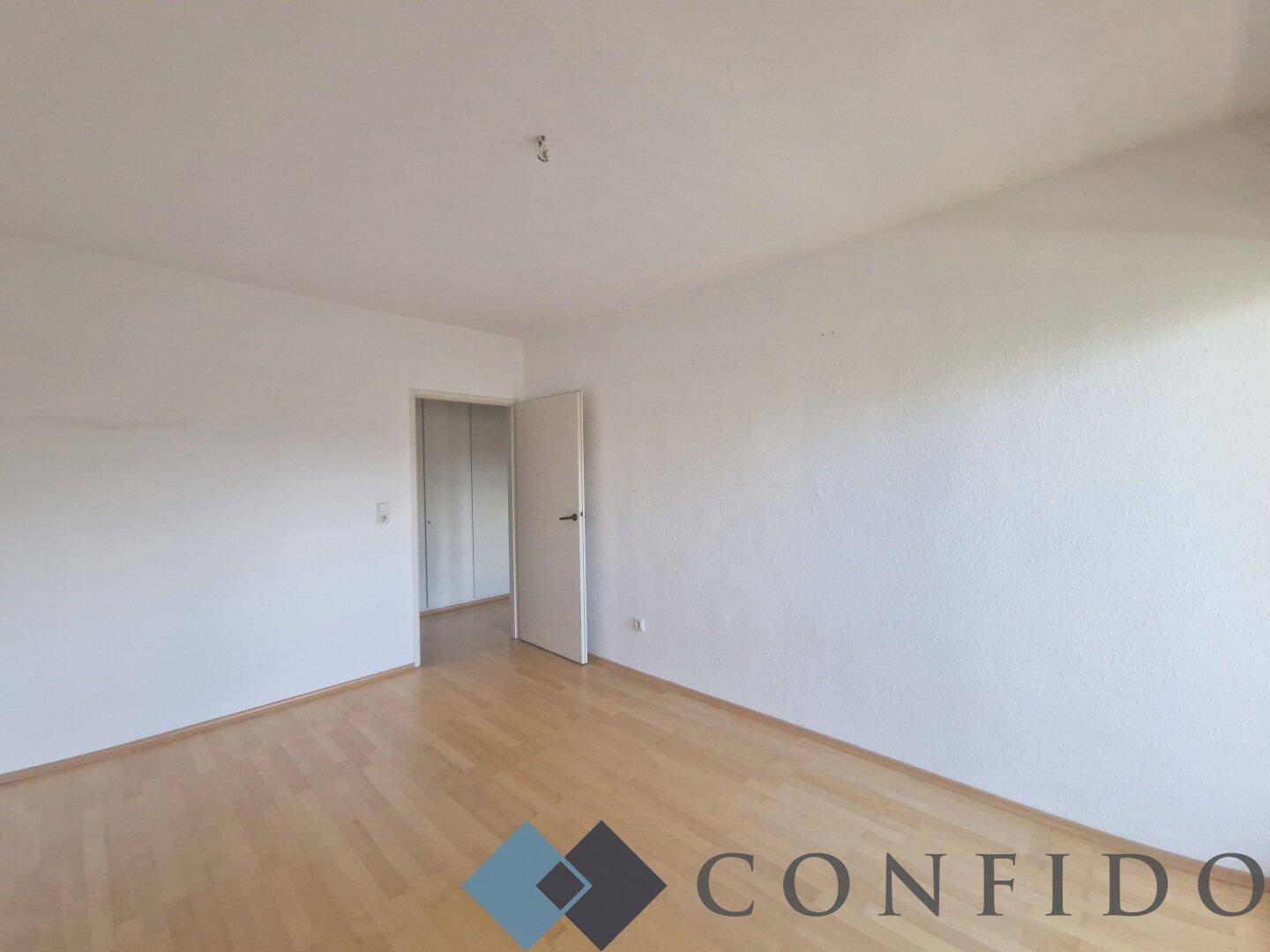 Leeres Schlafzimmer mit Holzboden und weiß gestrichenen Wänden, bietet viel Potenzial.