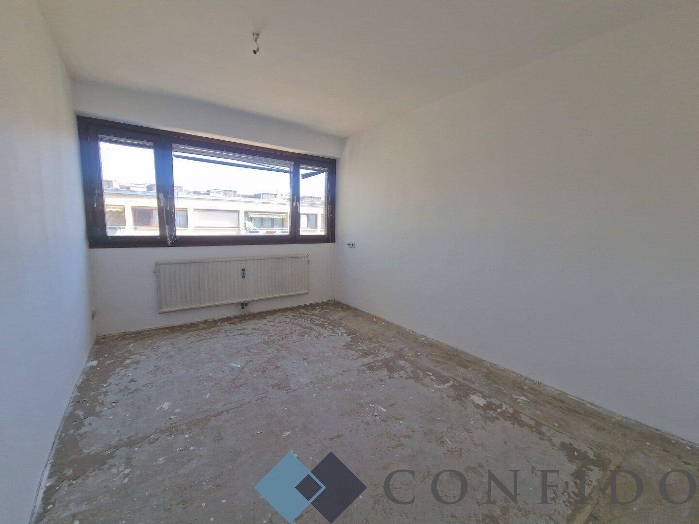 Unmöbliertes Schlafzimmer mit Fenster und Heizkörper, bereit für die individuelle Gestaltung.